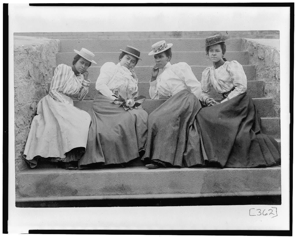 Four African American women seated on steps of building at Atlanta University, Georgia, photographer Askew, Thomas E.